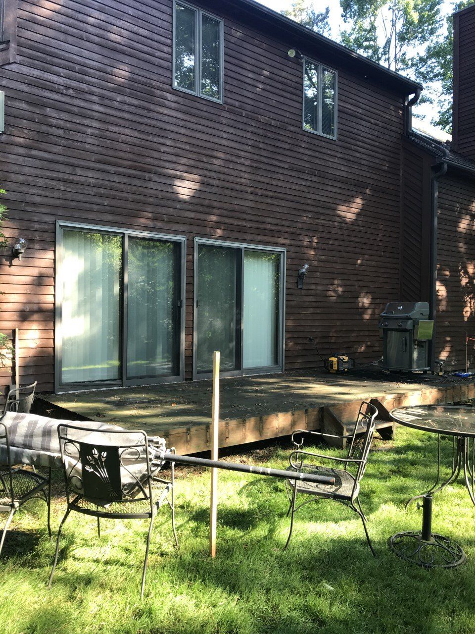 A brick house with a wooden deck and patio furniture in front of it.