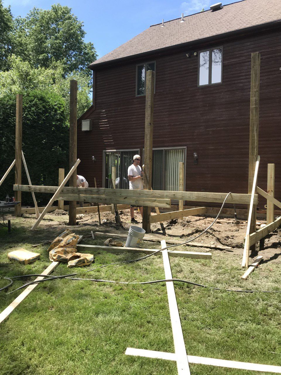 A man is working on a wooden deck in front of a house.