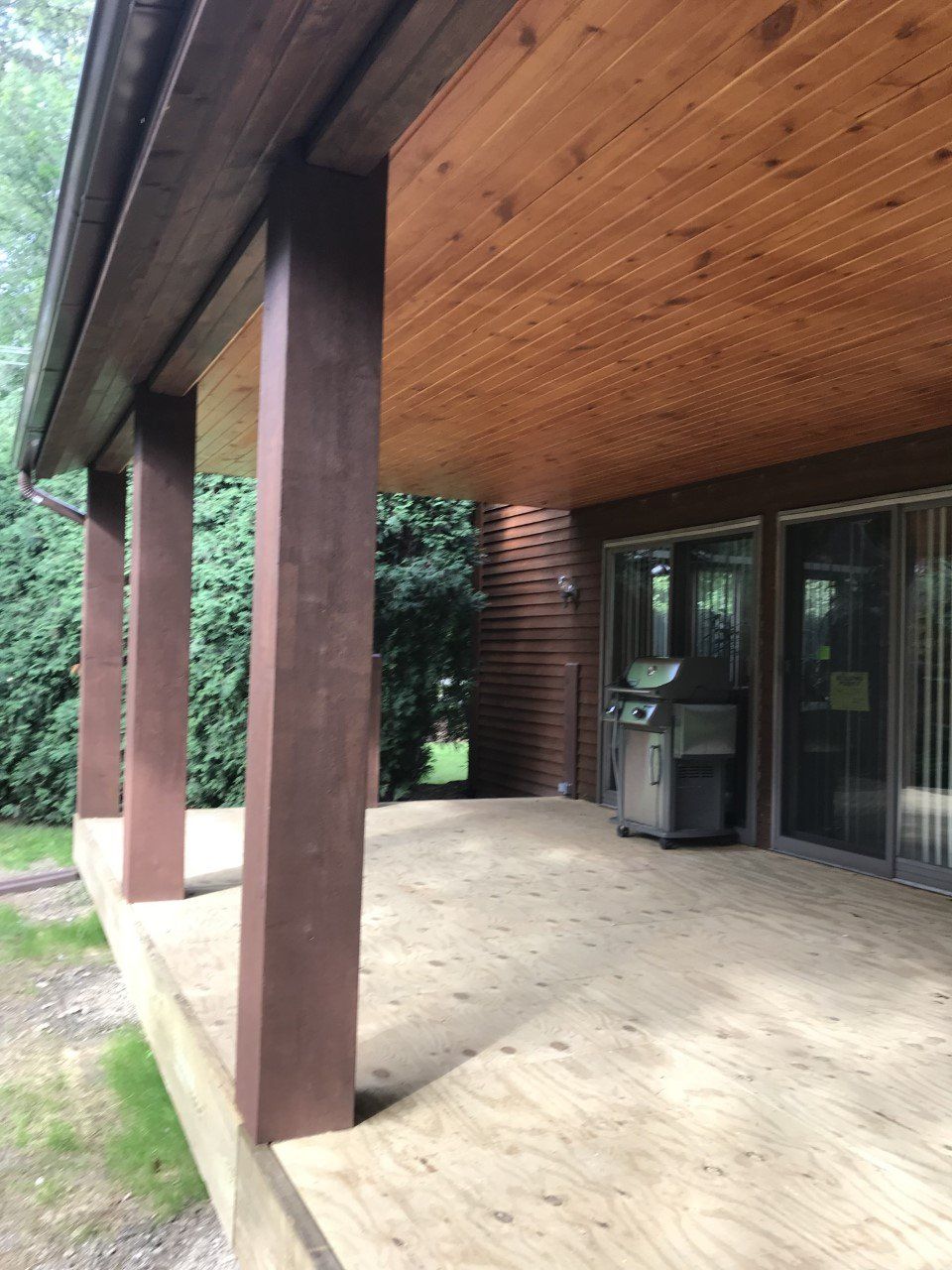 A wooden porch with a grill and sliding glass doors
