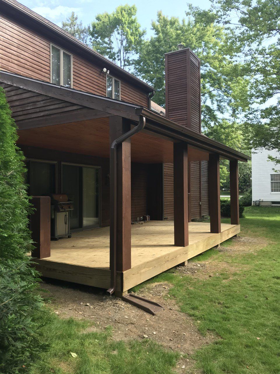 A house with a porch and a chimney in the backyard