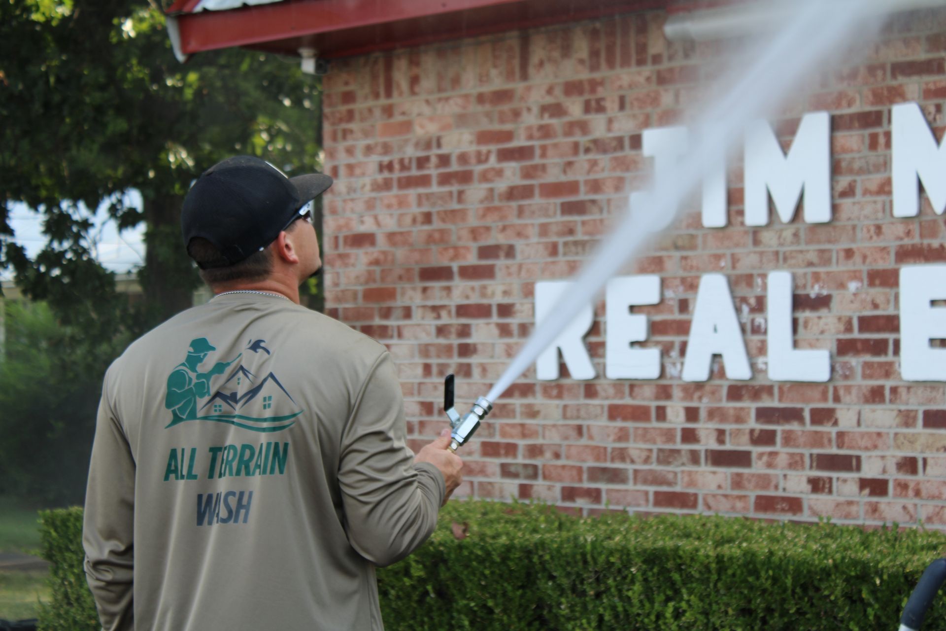 Man power washing brick wall with 