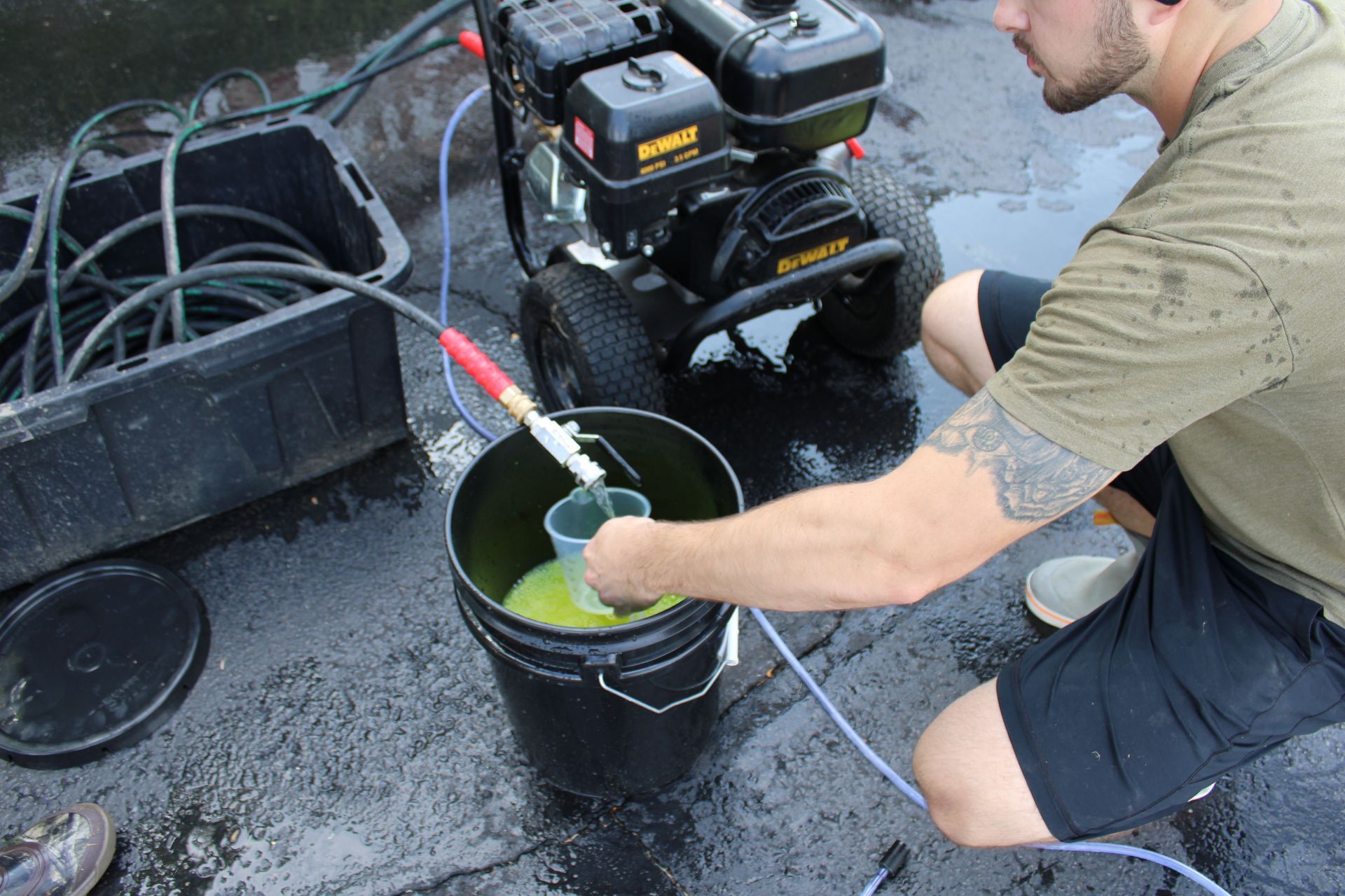 Man preparing pressure washer, mixing liquid in bucket outside.