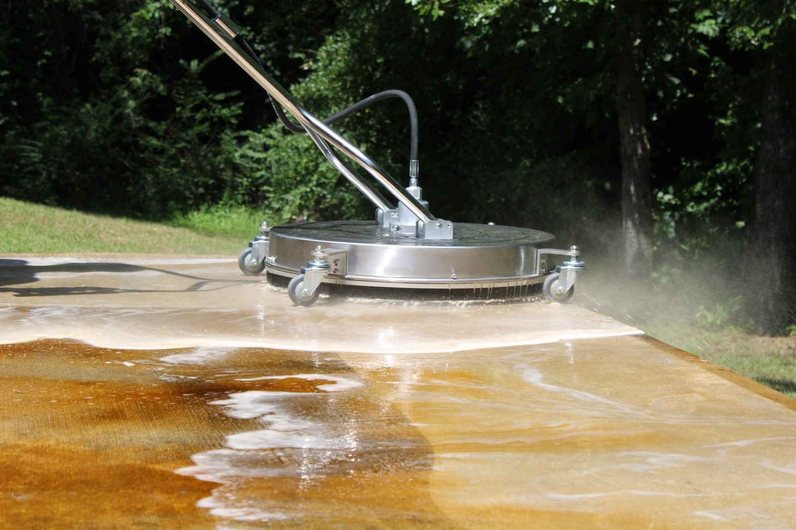 Pressure washer cleaning a concrete surface, removing dirt and stains.