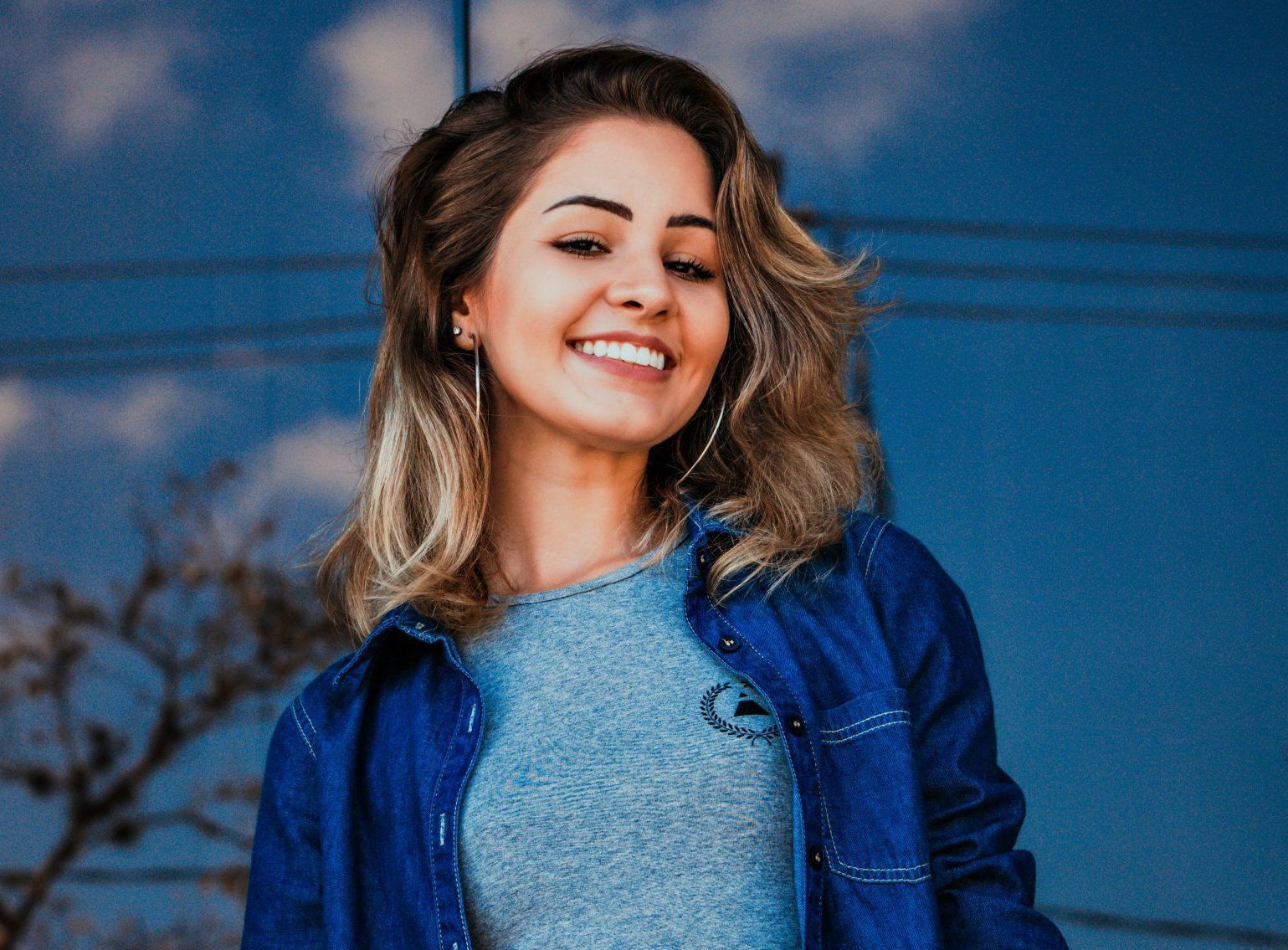 A woman wearing a blue jacket and a blue shirt is smiling.