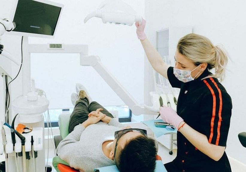 A dentist is examining a patient 's teeth in a dental office.