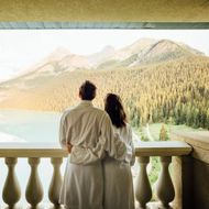 Un uomo e una donna sono in piedi su un balcone che guarda verso un lago