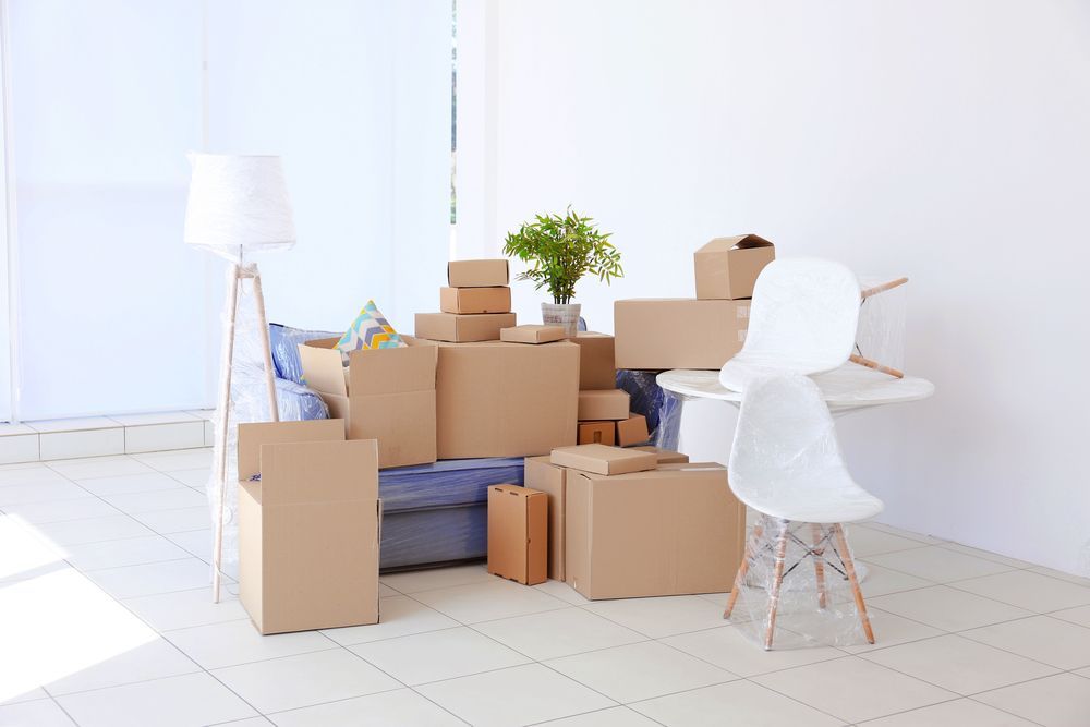 a living room filled with lots of cardboard boxes and furniture .