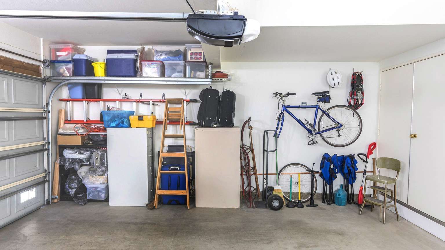 a garage filled with lots of items and a bicycle hanging on the wall .