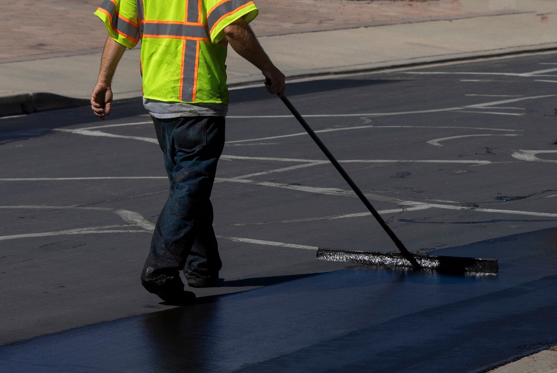 A man is walking down a street with a mop.