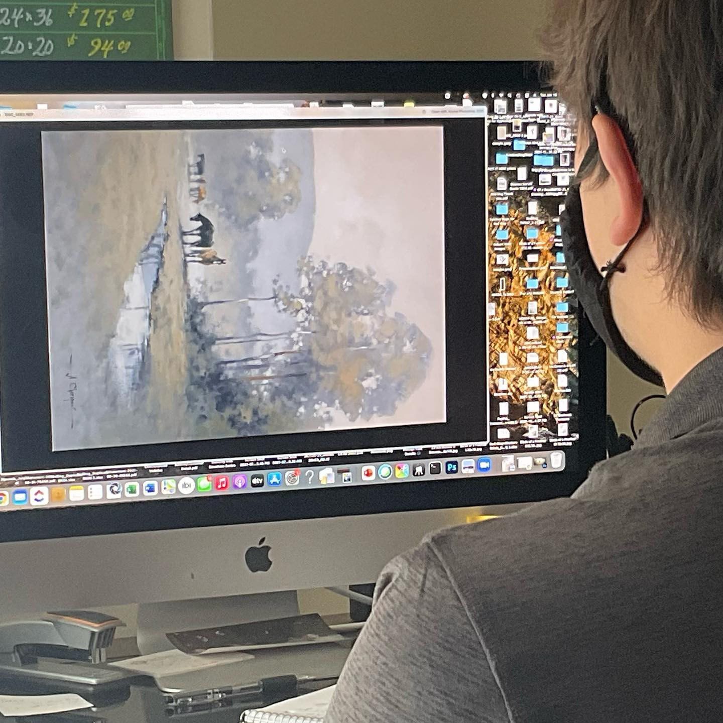 A man wearing a mask is looking at an apple computer screen