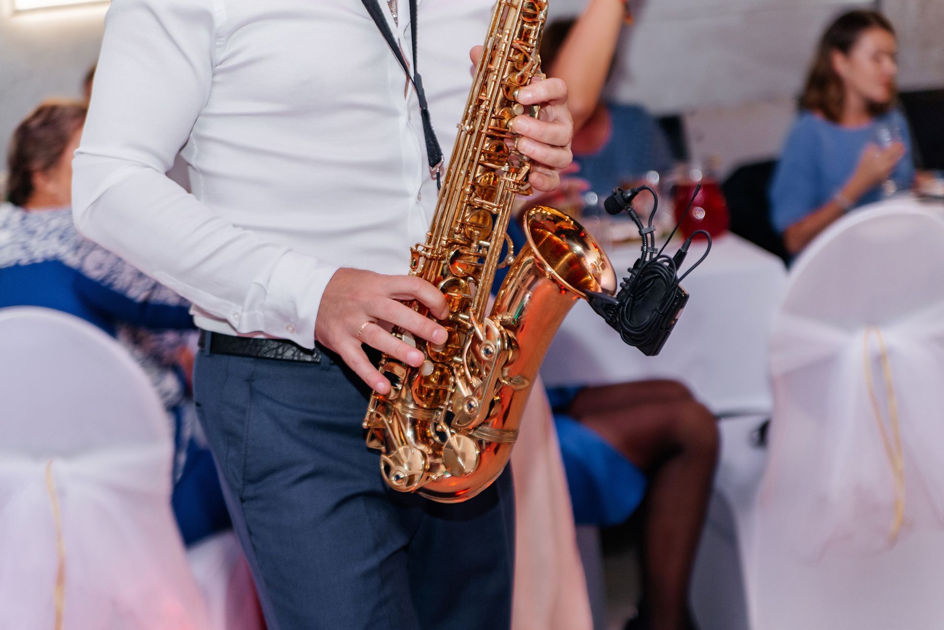 Person playing a gold saxophone at a formal indoor event