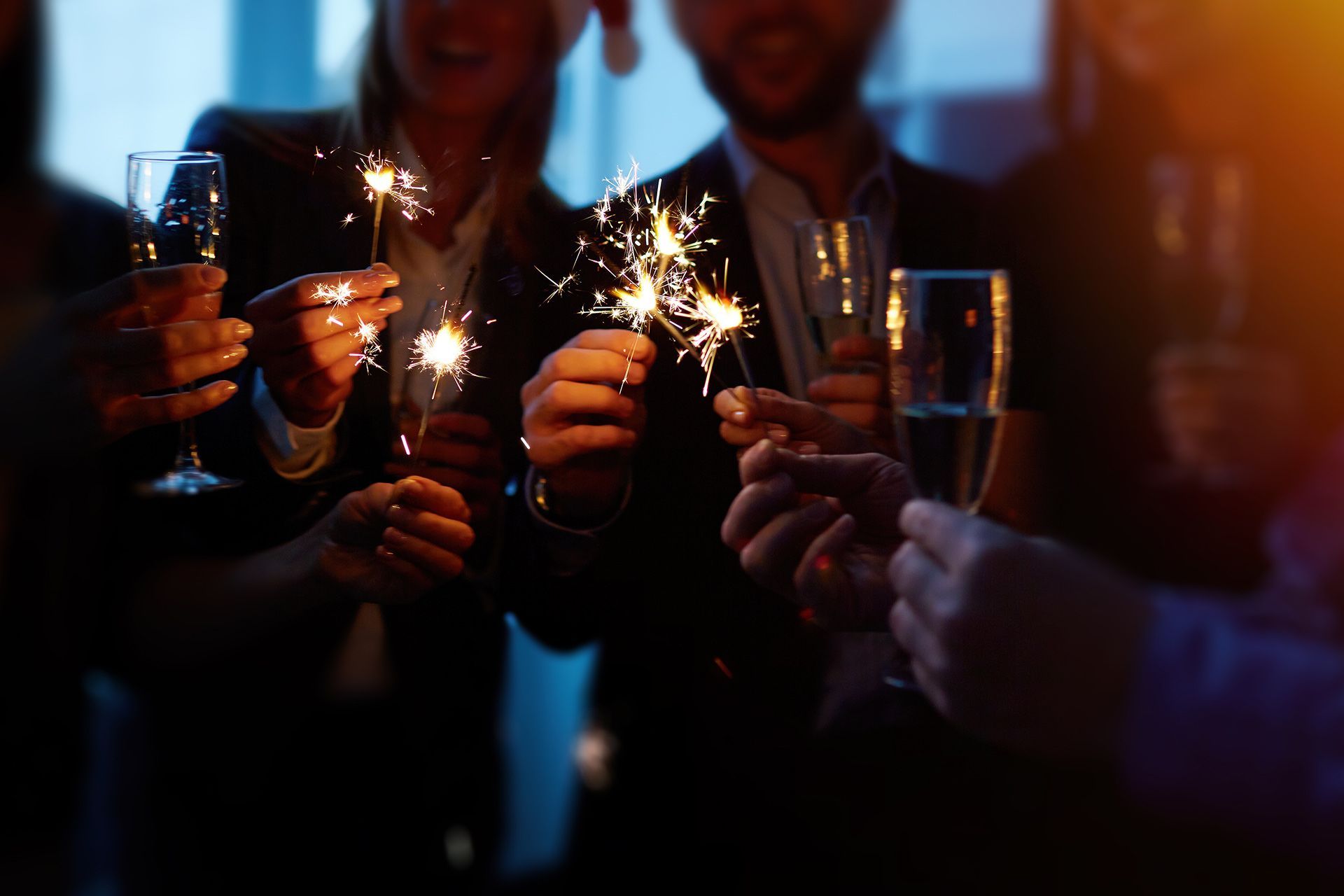 People holding sparklers and champagne glasses at a dimly lit celebration