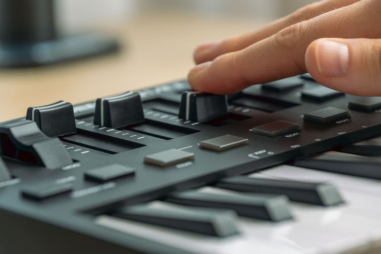 Finger adjusting knobs on a black audio mixer console