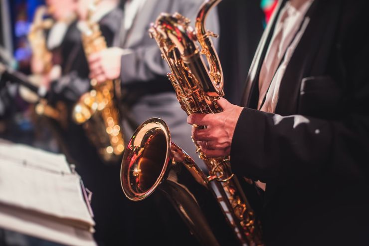 Musicians in suits holding saxophones during a performance, with warm stage lighting.