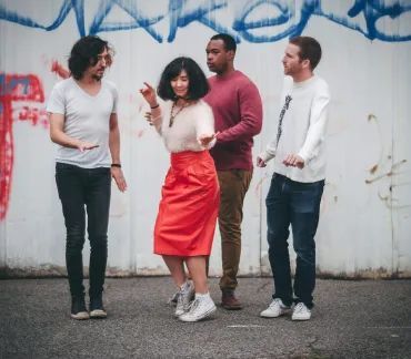 Four friends chatting outdoors in front of a graffiti-covered wall.