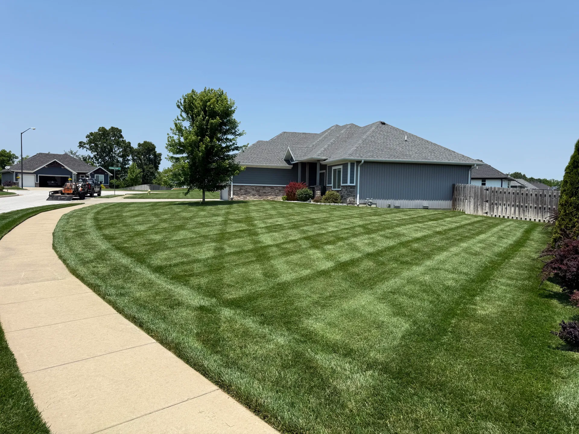 A neatly mown lawn with striped patterns in front of a gray single-story suburban house in springfield mo