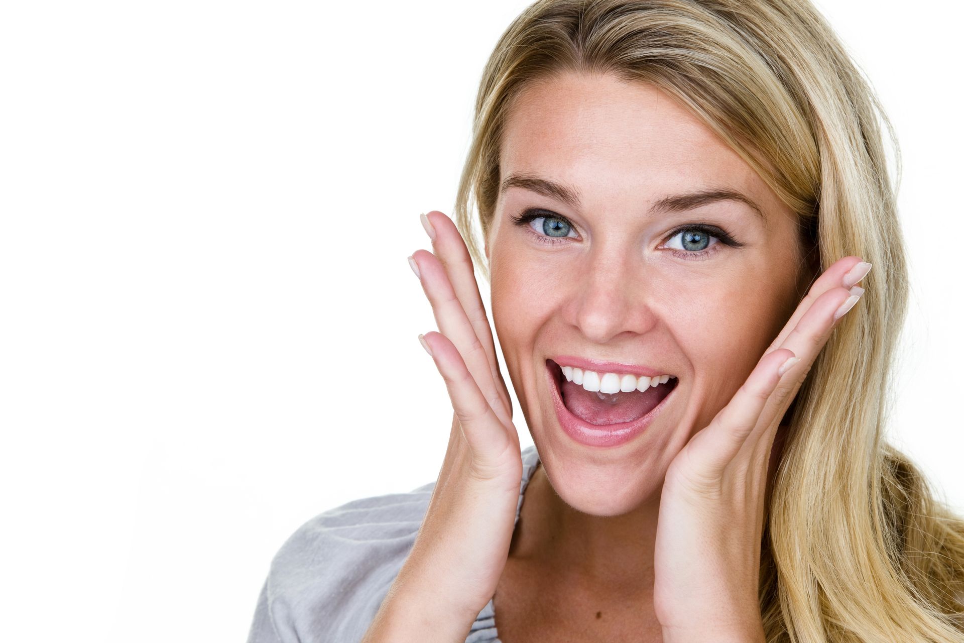 A woman is smiling with her hands on her face.