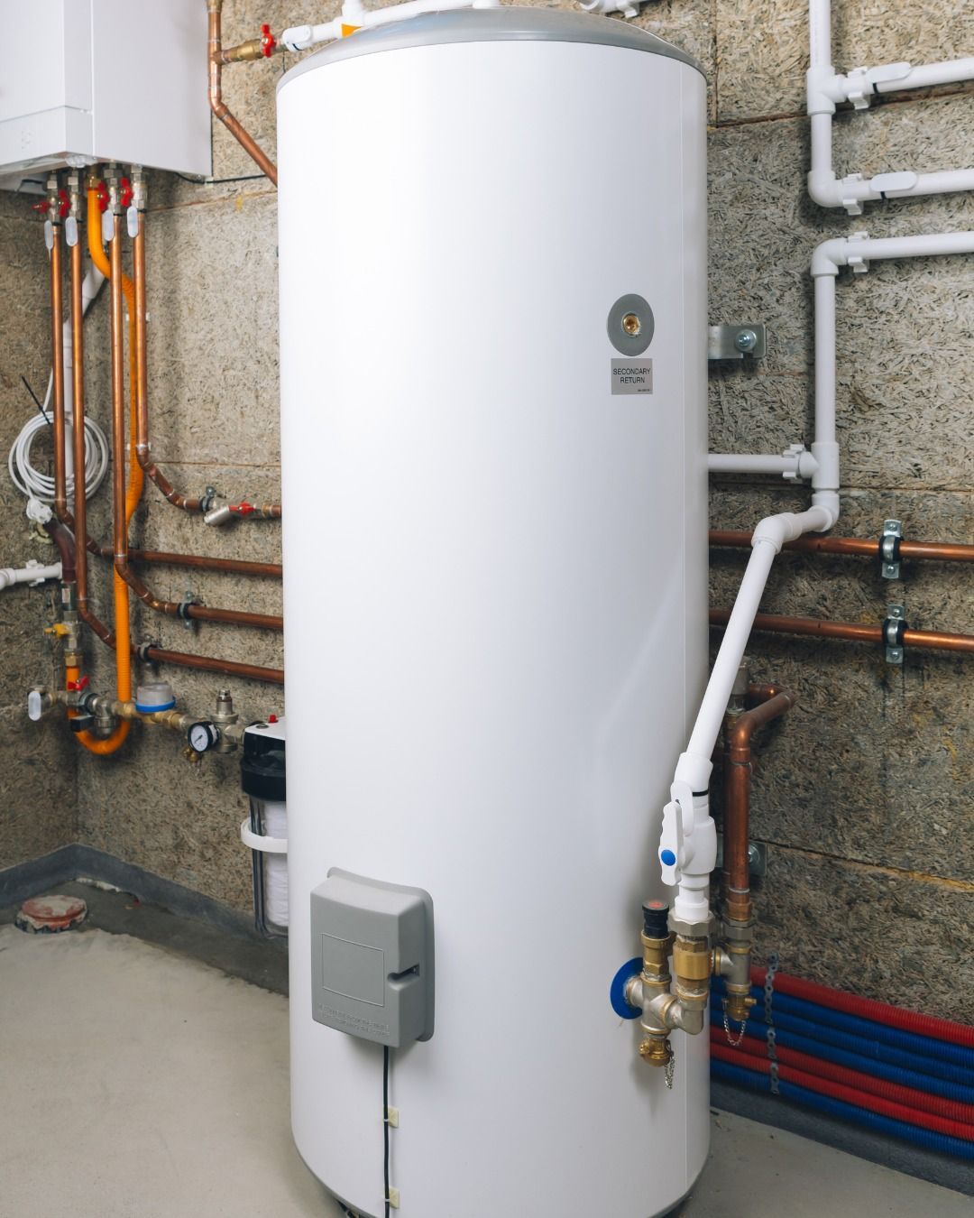 White hot water tank with copper and plastic pipes in a basement.