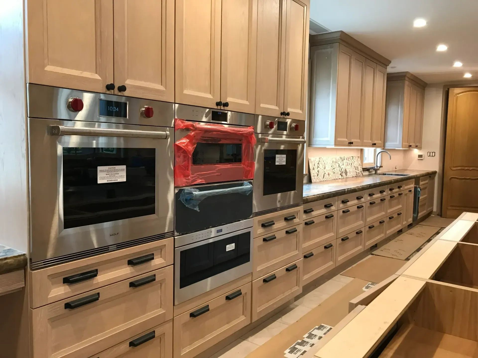 Kitchen with light-colored wood cabinets, stainless steel appliances, and drawers, under construction.