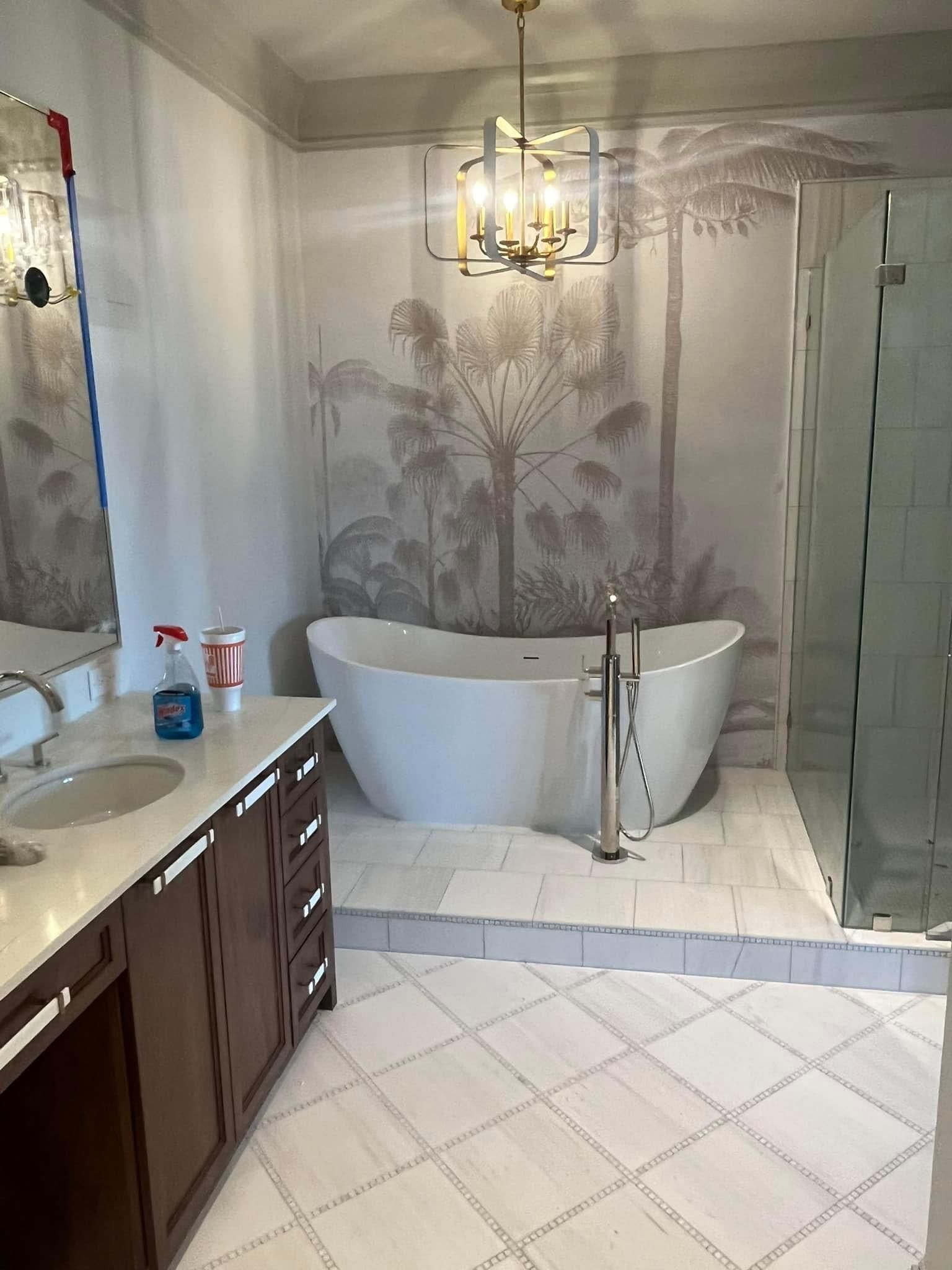 Bathroom with a white freestanding tub, palm tree mural, brown vanity, and tiled floor.