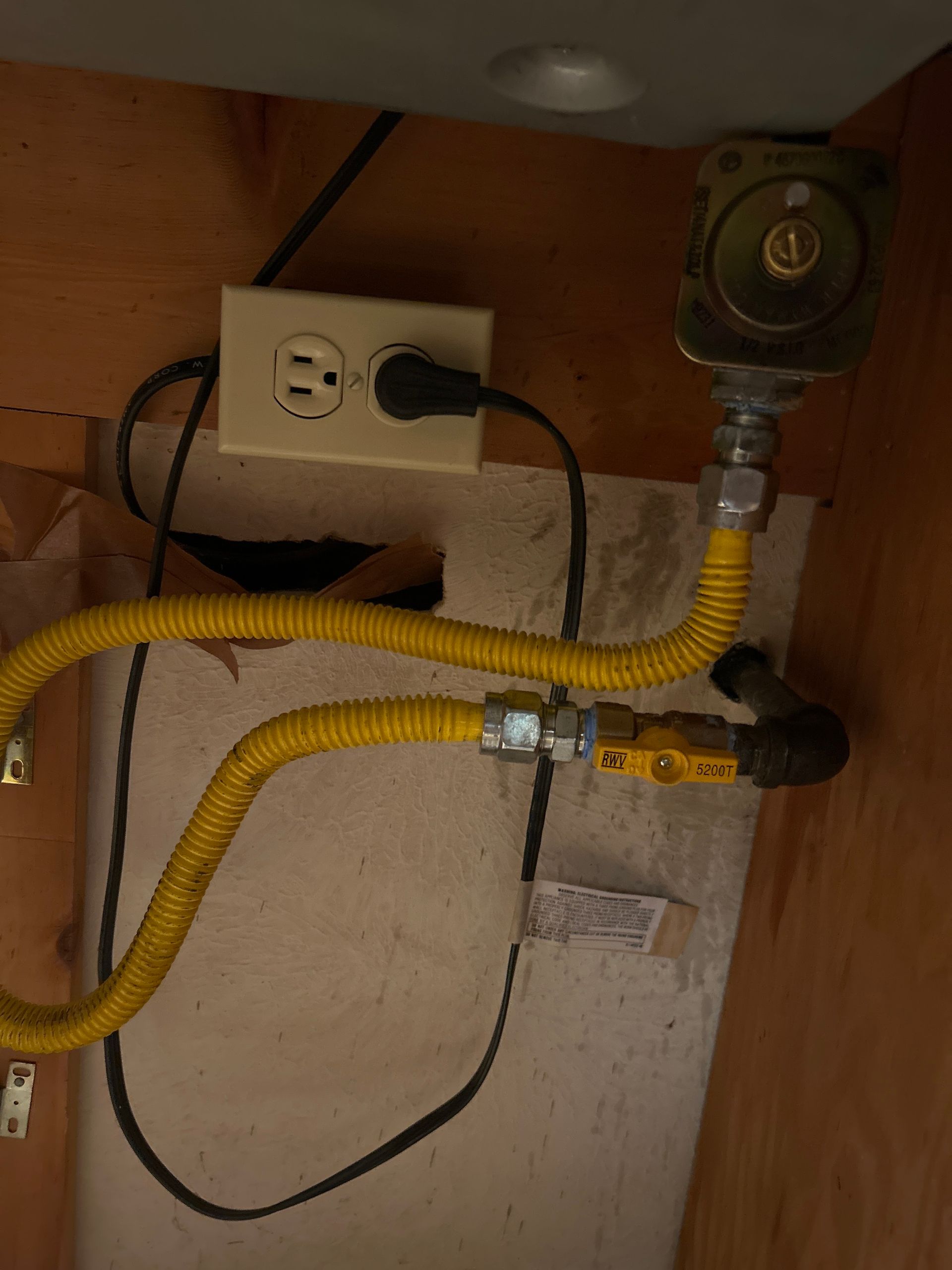 Yellow gas lines and electrical outlet in a wooden enclosure.