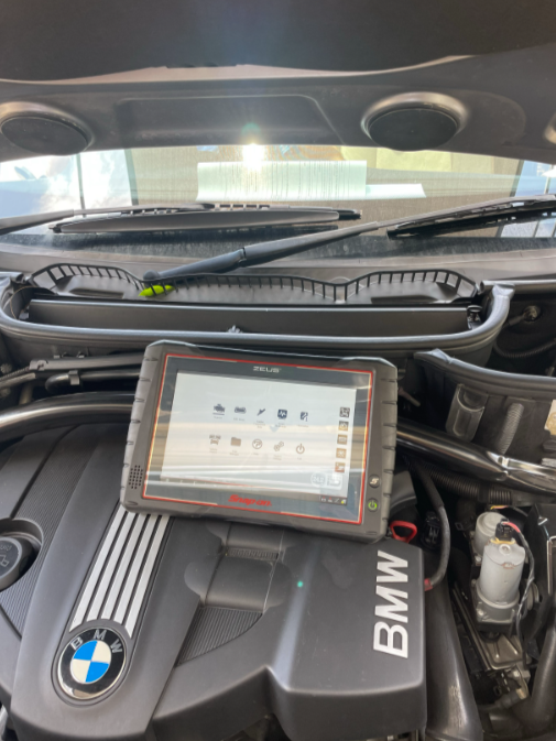 A Man Is Working On A Car With A Multimeter — Cabba Auto Electrics In Chinderah, NSW