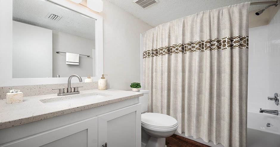 Bathroom with white cabinets, toilet, and a shower curtain.