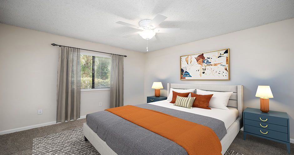 Bedroom with bed, nightstands, window, art, and ceiling fan. Gray, orange, and blue color scheme.
