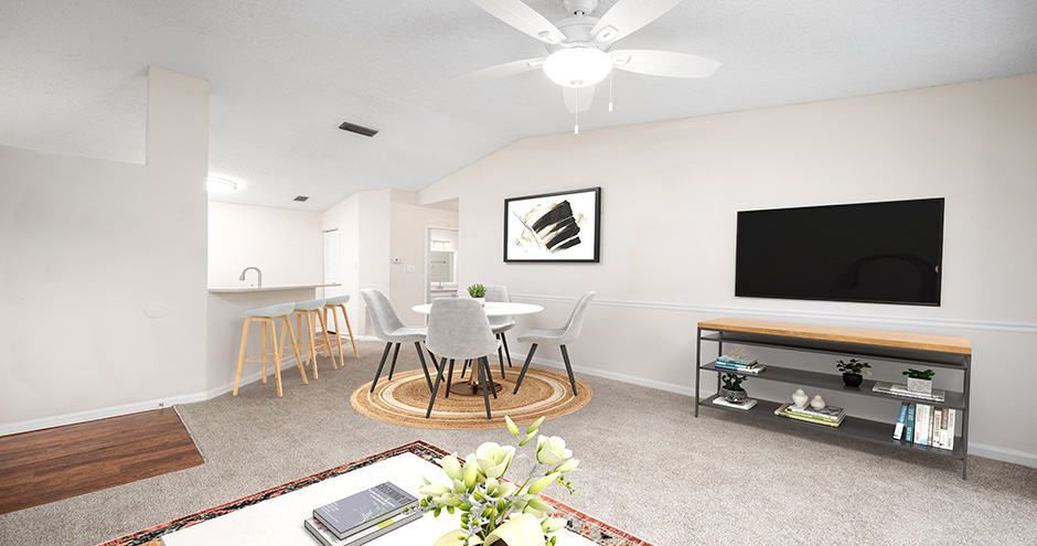 Living room with a dining area, featuring a TV, round table, and neutral color scheme.