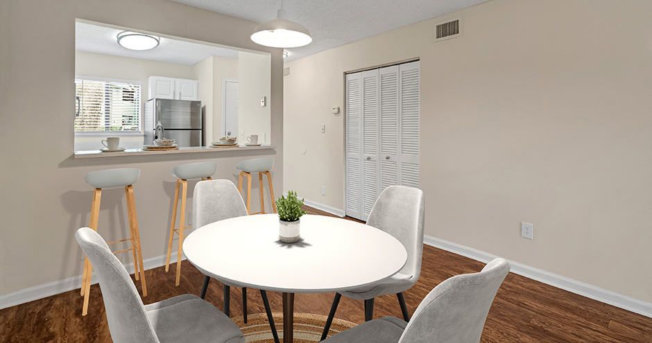 Dining area with round table and chairs, connected to kitchen with a breakfast bar.