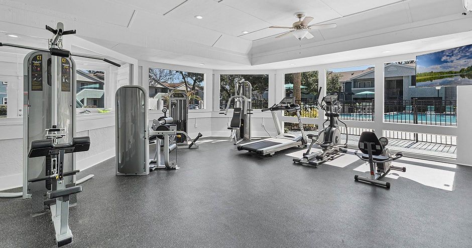 Gym with exercise equipment, including weight machines, treadmills, and a stationary bike.