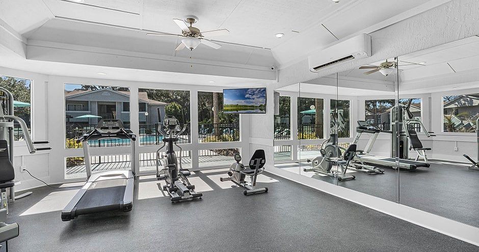 Gym with fitness equipment, large windows, and a mirrored wall.