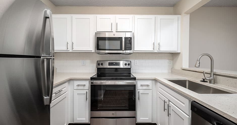 Modern kitchen with white cabinets, stainless steel appliances, and a quartz countertop.