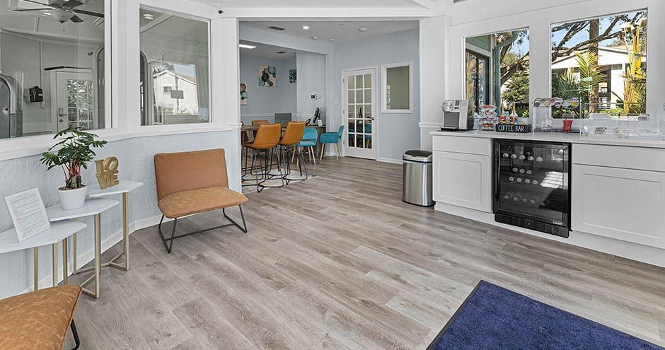 Bright waiting room with tan and blue chairs, white cabinets, and a bar area.
