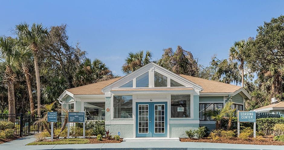 Blue and white building with a pitched roof, palm trees, and sign boards.