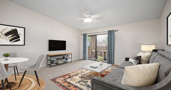 Living room with gray sofa, TV, table, and a door leading to a balcony.