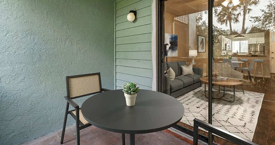 Patio with black table and chair set. Open door reveals living room.