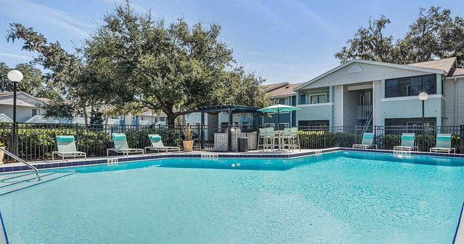 Swimming pool at apartment complex with lounge chairs and bar area.