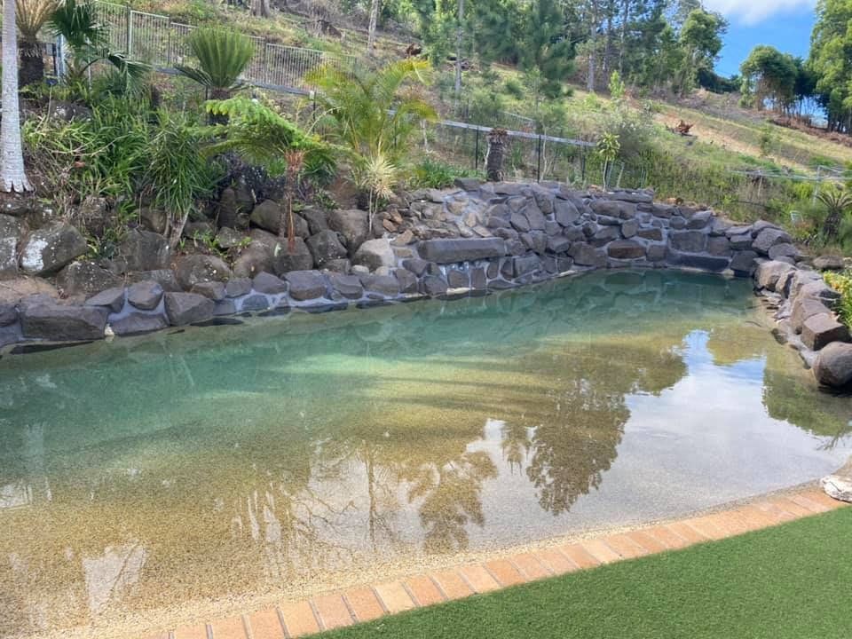 A Large Pond Surrounded by Rocks and Trees in a Backyard — Jaiden Tanners Water Supplies in Murwillumbah, NSW