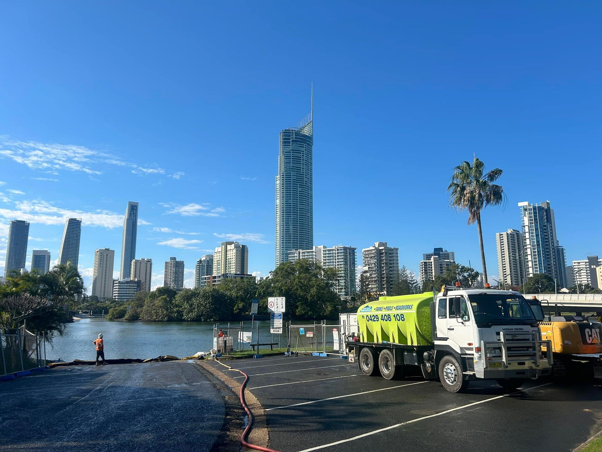 A White Truck With a Green Tank on a Parking Lot with Q1 in the Background — Jaiden Tanners Water Supplies in Murwillumbah, NSW
