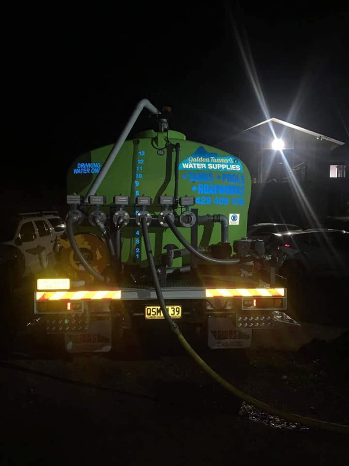 A Green Water Truck is Parked in a Parking Lot at Night — Jaiden Tanners Water Supplies in Murwillumbah, NSW