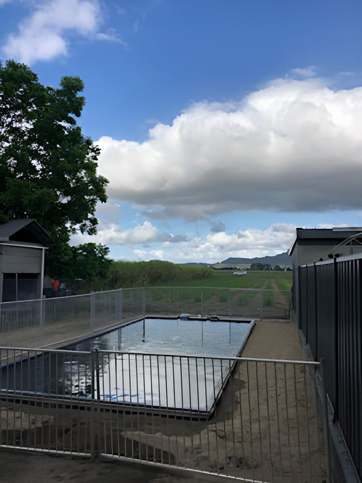 A Large Swimming Pool Surrounded by a Fence on a Sunny Day — Jaiden Tanners Water Supplies in Mullumbimby, NSW