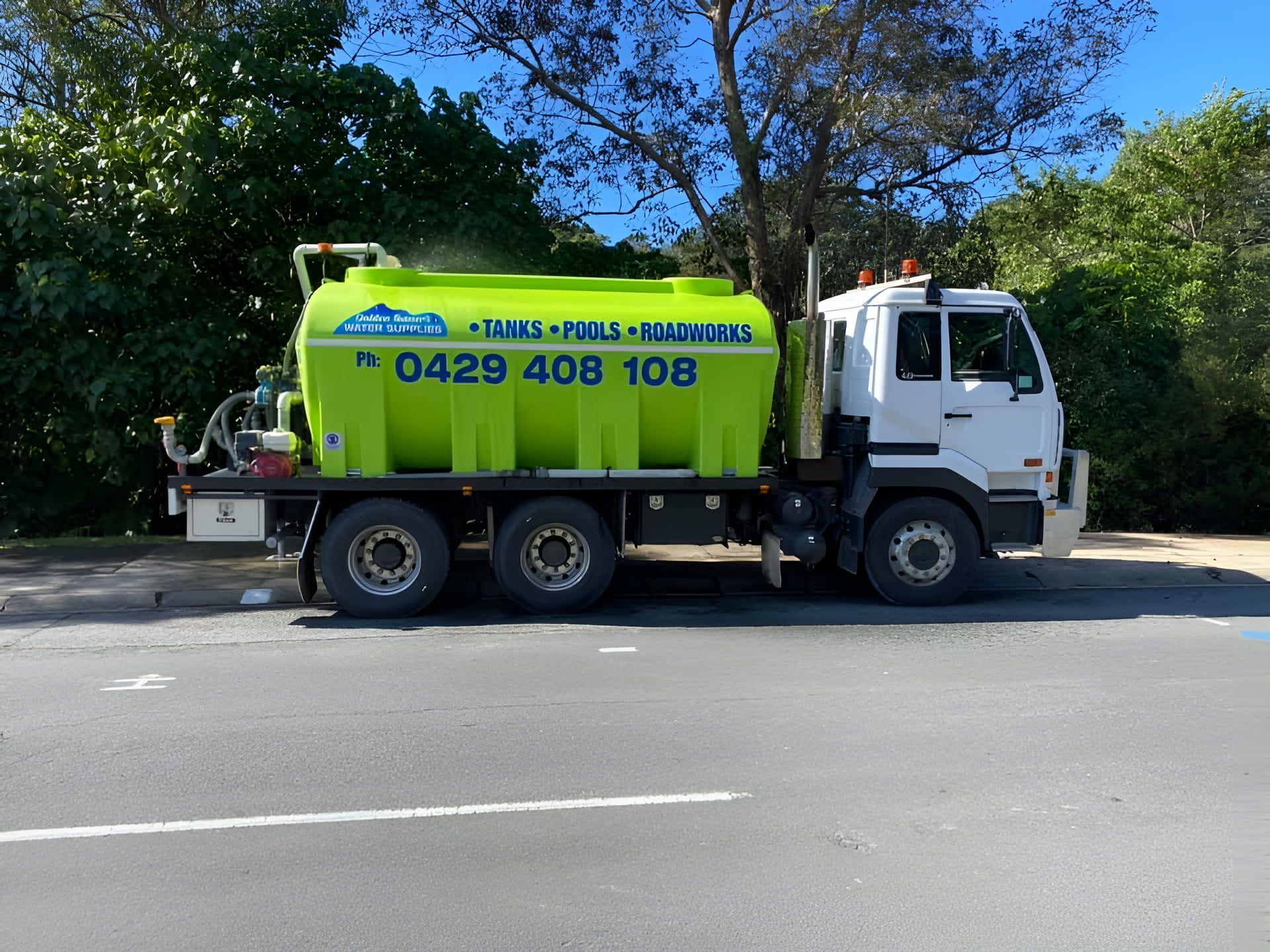 A Yellow Truck is Spraying Water on a Dirt Road — Jaiden Tanners Water Supplies in Nimbin, NSW