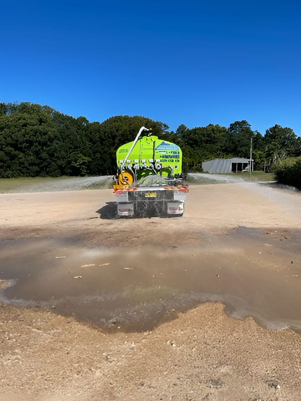 A Truck is Spraying Water on a Dirt Field With Mountains in the Background — Jaiden Tanners Water Supplies in Mullumbimby, NSW