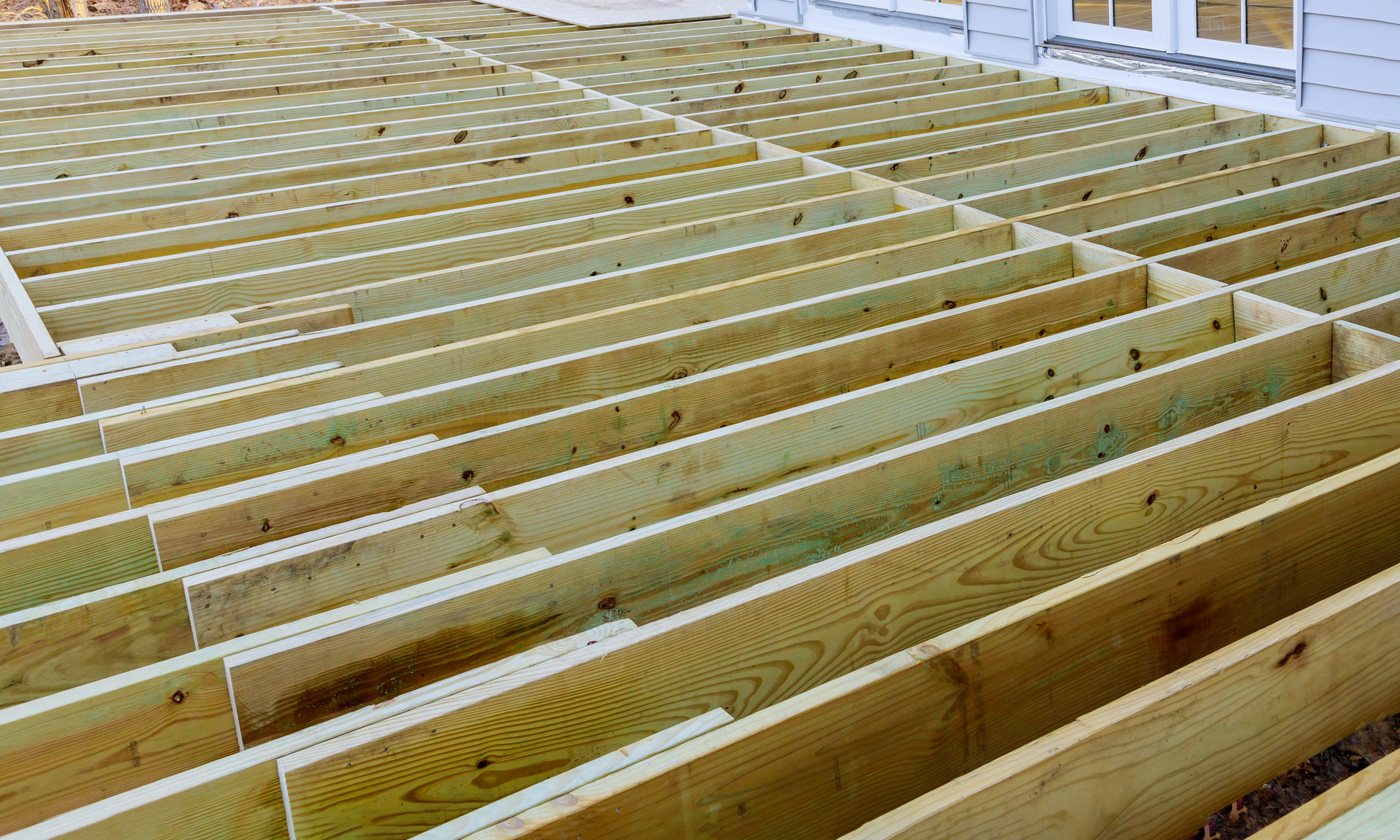 A photo of a deck in the process of being built. There is no decking installed yet only support beams in the photo.