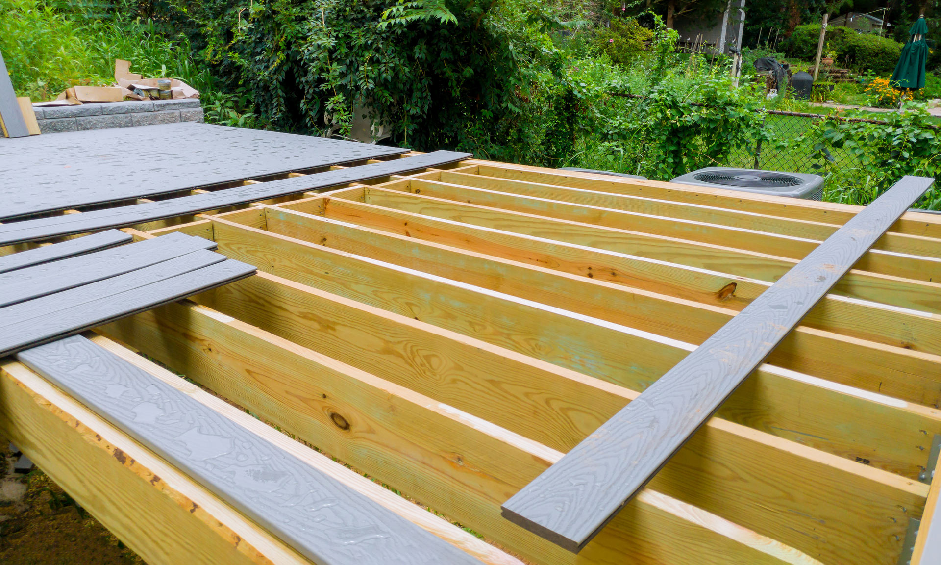 photo of a deck that has just begun installing composite decking boards on the framework of a new deck.