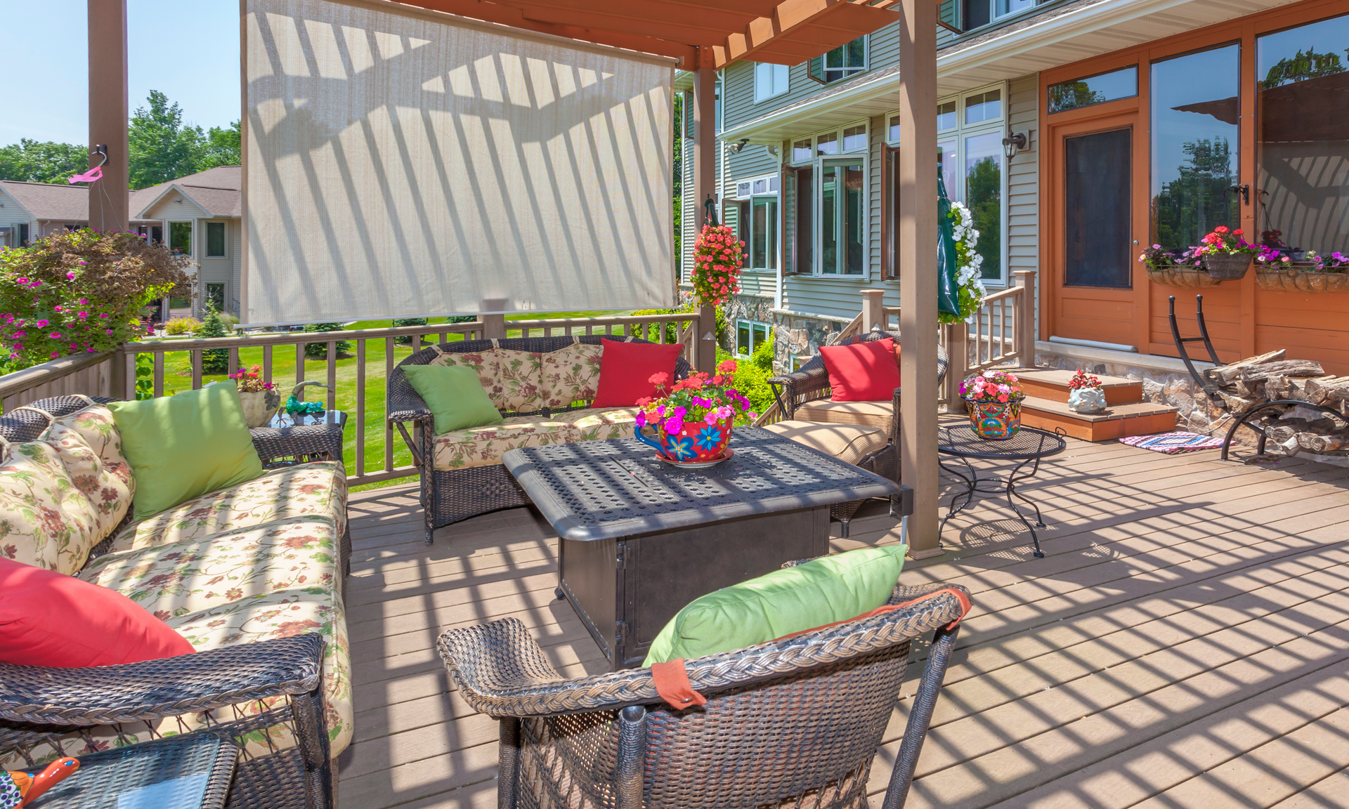A photo of a beautiful backyard deck with plenty of lawn furniture and decorations to make the deck look comfy and cozy.