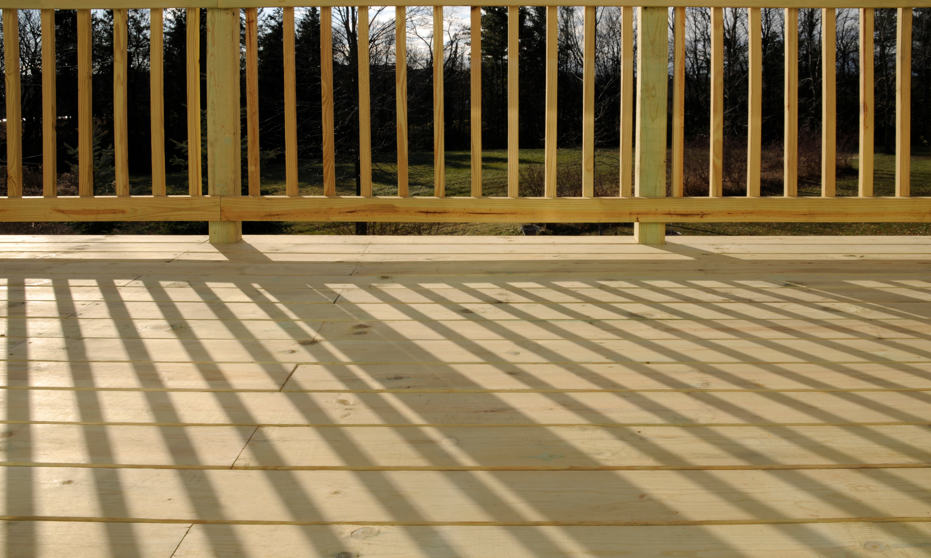 Photo of a brand new deck with fresh wood and railing.