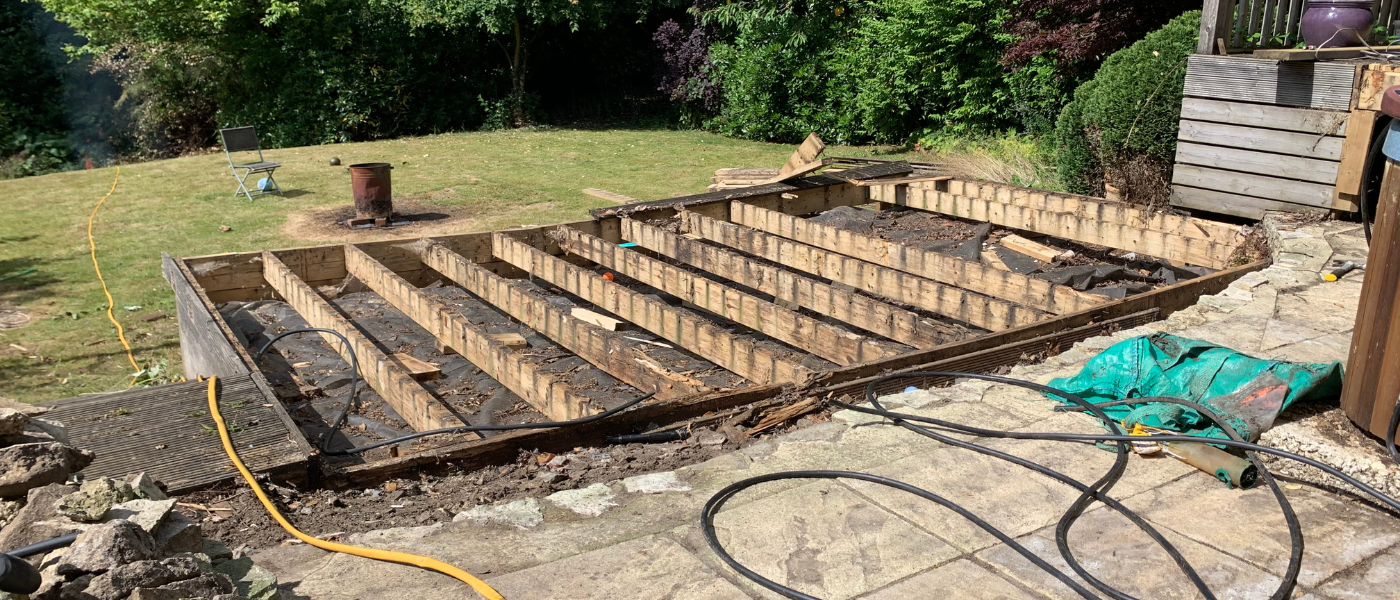 A photo of a deck that is in the process of being removed. THe decking boards are already removed and all that is left is the structural frame of the deck. 