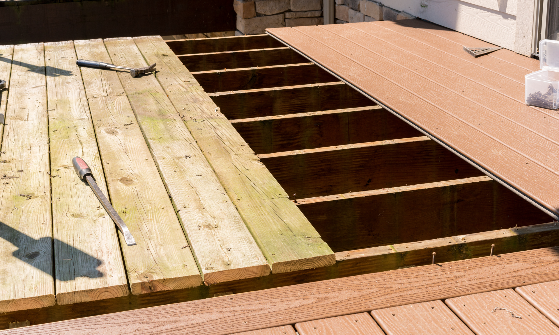 photo of an old deck that is getting i's old traditional wood decking ripped out and is getting composite decking materials installed as a replacement.